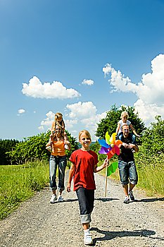 Happy family walking down a path on a bright summer day