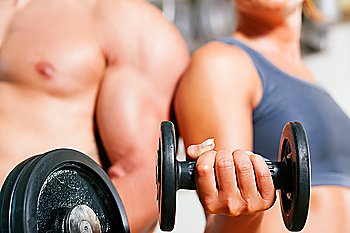 Couple exercising with dumbbells in a gym, focus on eyes of man and woman