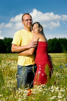 Couple in love kissing each other, standing in a field with wild flowers