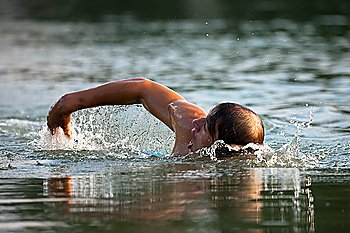 Very athletic man swimming in a wonderful soft late afternoon light
