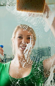 Young woman cleaning her windows with spray and sponge