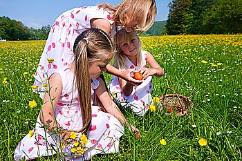 Children on an Easter Egg hunt on a meadow in spring