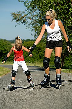 young mother roller skating with her daughter