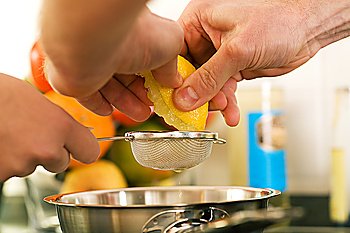 People cooking, squeezing a lemon in order to prepare dessert