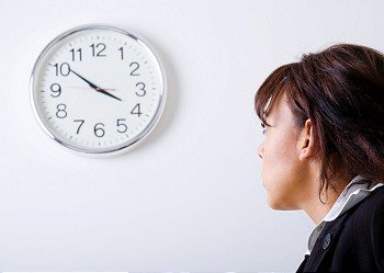 Female office worker looking at a clock on the wall