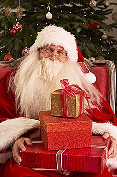 Santa Claus Sitting In Armchair In Front Of Christmas Tree