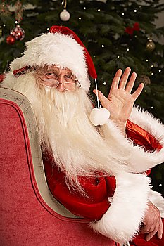 Santa Claus Sitting In Armchair In Front Of Christmas Tree