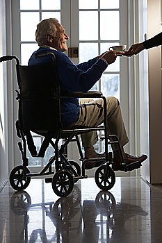 Disabled Senior Man Sitting In Wheelchair Being Handed Cup 