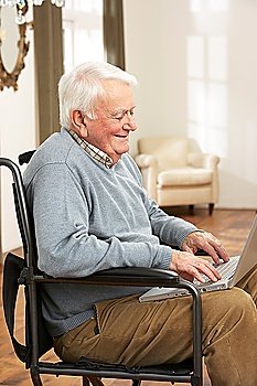 Disabled Senior Man Sitting In Wheelchair Using Laptop