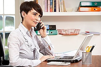 Woman Working From Home Using Laptop On Phone