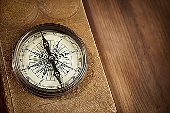 vintage concept with old compass and atlas on wooden background selective focus on nearest part