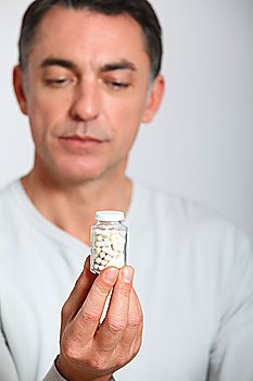 Closeup of man holding bottle of pills
