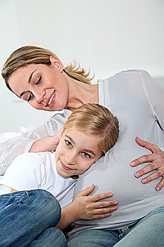 Little blonde girl listening to pregnant woman belly