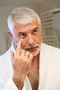 Portrait of senior man applying moisturizing cream