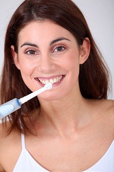 Young woman brushing her teeth with electric toothbrush