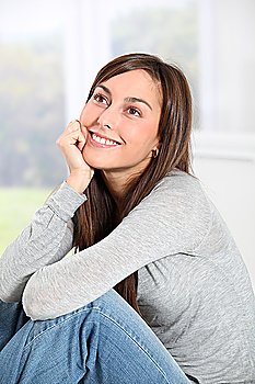 Smiling young woman at home sitting on sofa