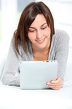 Young woman laying on sofa with electronic pad