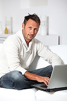 Man with laptop computer sitting in sofa