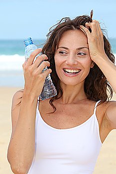 Beautiful woman drinking water at the beach