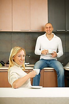 Laughing pair drinks morning coffee on kitchen