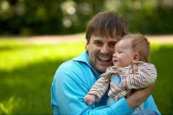 Happy pair - the father and the baby-son in embraces each other on a background of a lawn