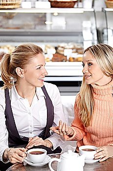 Two young attractive girls communicate in cafe 