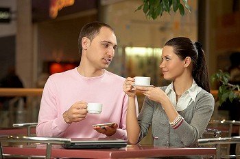 The couple talks in cafe behind a coffee cup