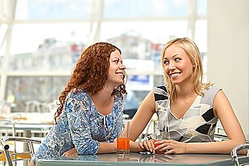 Two young women in a cafe look in one side