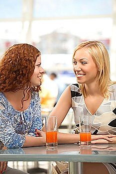 Two girls in cafe look against each other and smile