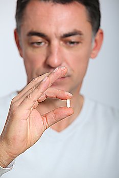 Man looking closely at pill