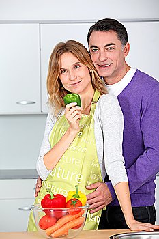Couple in kitchen with bowl of vegetables