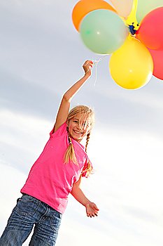 Little girl holding balloons out in the countryside