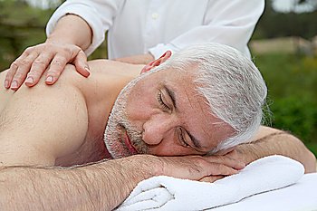 Portrait of senior man laying on a massage bed
