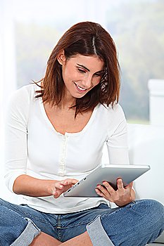 Young woman sitting on sofa with electronic tablet