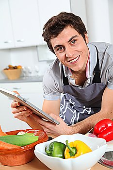 Man in kitchen looking at recipe with electronic tab