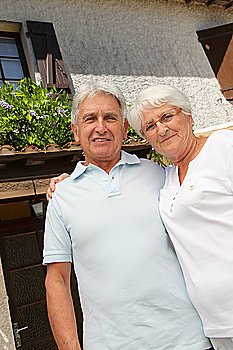 Senior couple standing in front of a house
