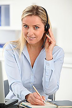 Blond woman in the office with headset on