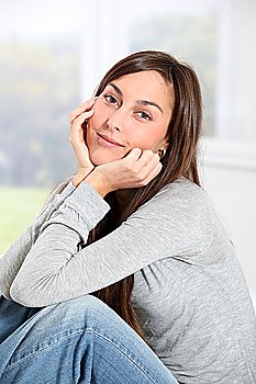 Smiling young woman at home sitting on sofa