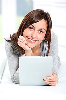 Young woman laying on sofa with electronic pad