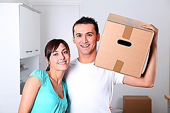 Young couple carrying boxes into new house
