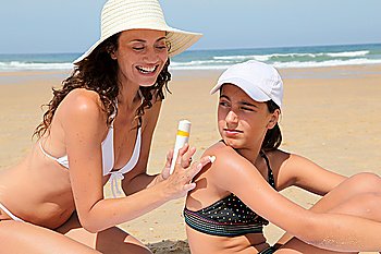 Mother spreading sunscreen on her daughter´s shoulders