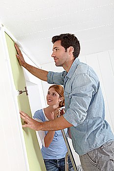 Couple putting new wallpaper in room