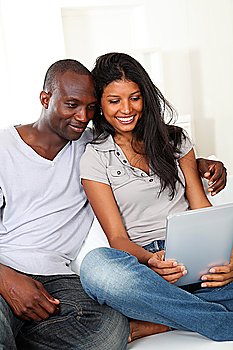 Happy loving couple sitting in sofa with electronic tablet