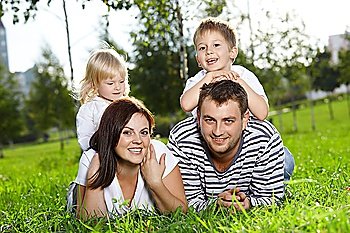 Happy family from four persons lies on a summer lawn