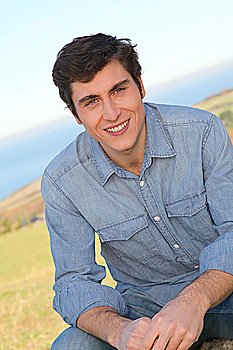Portrait of smiling handsome man sitting in country field