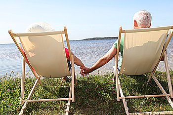 Senior couple in deck chairs in front of a lake
