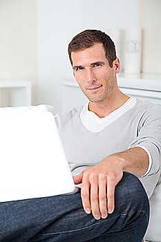 Closeup of adult man sitting on sofa with laptop computer