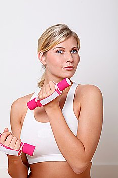 Beautiful blond woman lifting dumbbells in fitness gym