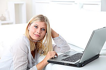 Beautiful blond woman with headphones in front of laptop