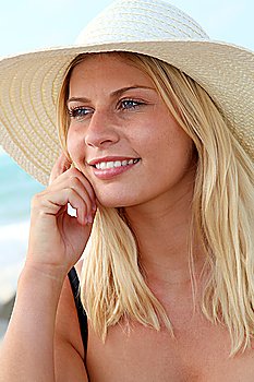 Closeup of beautiful blond woman wearing hat at the beach